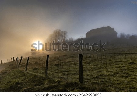Sunrise on a foggy morning, beautiful landscape, house on the mountain, wire fence.