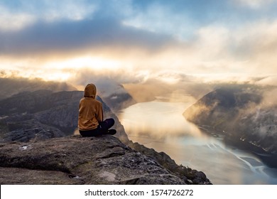 Sunrise on pulpit rock. Girl looking on fjord - Shutterstock ID 1574726272