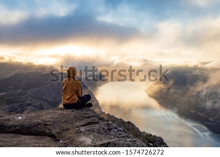 Sunrise on pulpit rock. Girl looking on fjord