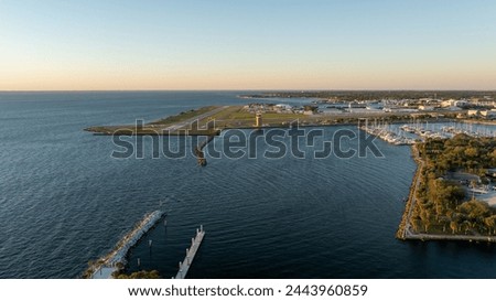 Sunrise over Albert Whitted Airport in St. Petersburg, with calm waters and docked boats nearby, cityscape in the distance.