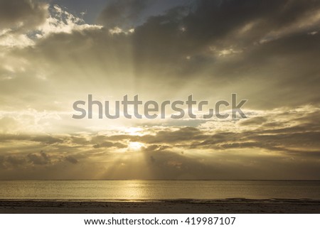 Sunrise over beach and ocea with beautiful colorful clouds and rays of lights