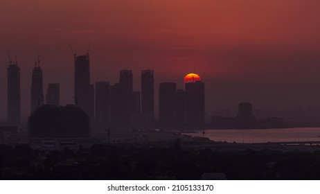 Sunrise Over Dubai Creek Harbor With Skyscrapers And Towers Under Construction Aerial Timelapse. Big Red Sun Rise Up Behind Buildings