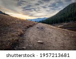 Sunrise over high elevation peaks with Herman Gulch trail leading into the tree horizon