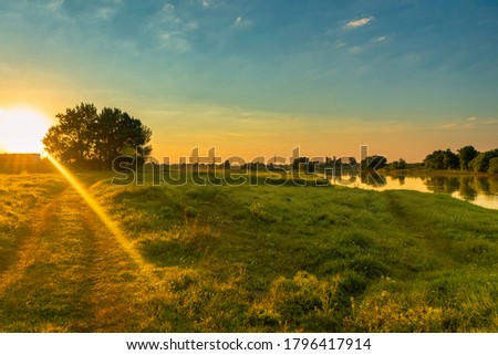 Sunrise over the meadow with river on a side
