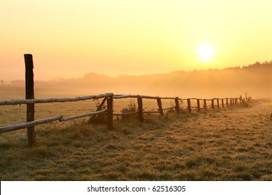 Sunrise over misty grassland with wooden fence in the foreground. Photo taken in October. - Powered by Shutterstock