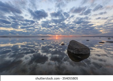 Sunrise over the sea with clouds reflected in the still water