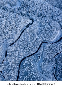 Sunrise Overhead Drone Shot Of A Mountain Alpine Road In A Snow Covered Forest And Snow Laden Pines In Early Morning In Deep Winter In Switzerland.