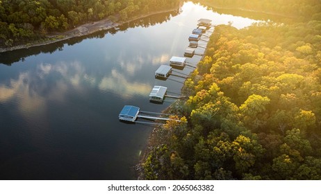 Sunrise photo over lake tenkiller in Oklahoma. Early fall drone photo showing leaves starting to turn on trees. Sunrise orange glow creates reflections on water and boat houses along the banks
