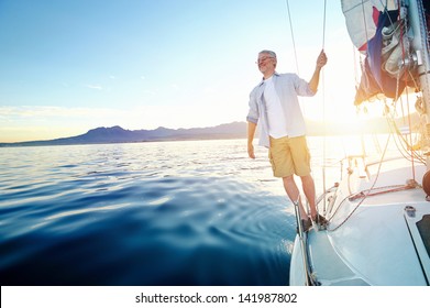 sunrise sailing man on boat in ocean with flare and sunlight on calm morning on the water