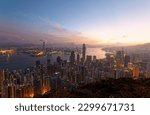 Sunrise scenery of Hong Kong, viewed from top of Victoria Peak, with a city skyline of crowded skyscrapers by the harbour and Kowloon Downtown across the seaport under dramatic dawning sky