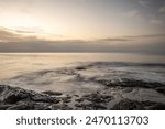 Sunrise with a sea view on a rocky coast in warm colors. Landscape with a lava stone beach at Tarajalejo on Fuerteventura, Canary Islands, Spain.