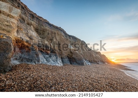 Sunrise seascape with cliffs showing different colour strata