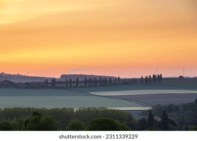Sunrise in spring time with the silhouette of the typical Tuscan Poplar trees in a line alongside a road during the golden hour and the sun on the horizon. - Shutterstock ID 2311339229