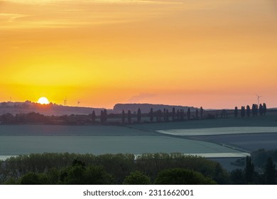 Sunrise in spring time with the silhouette of the typical Tuscan Poplar trees in a line alongside a road during the golden hour and the sun on the horizon. - Shutterstock ID 2311662001
