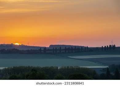Sunrise in spring time with the silhouette of the typical Tuscan Poplar trees in a line alongside a road during the golden hour and the sun on the horizon. - Shutterstock ID 2311808841