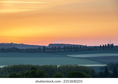 Sunrise in spring time with the silhouette of the typical Tuscan Poplar trees in a line alongside a road during the golden hour and the sun on the horizon. - Shutterstock ID 2311830231