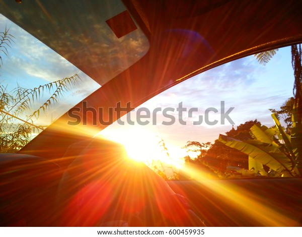 Sunrise taken from inside the car on a moving\
car. Sun flare from inside the\
car.