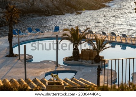 Sunrise in the traditional Mediterranean hotel on the rocky beach. Entry pool by the sea.