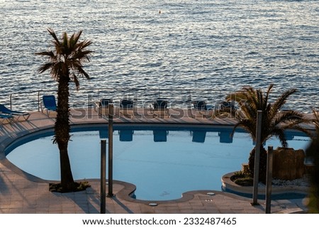 Sunrise in the traditional Mediterranean hotel on the rocky beach. Entry pool by the sea.