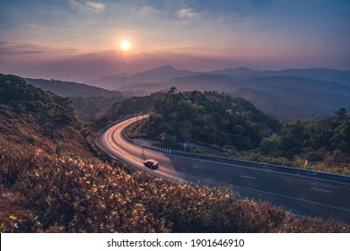 Sunrise View And Curved Road Reflex The Sun-ray With Mountainous View. Shallow Depth Of Field. Blurred Movement Car.