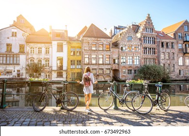 Sunrise view on the water channel with beautiful old buildings with woman standing near the bicycles in Gent city - Shutterstock ID 673492963