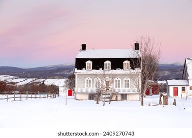 Sunrise winter view of beautiful patrimonial brick country house with metal Mansard roof and dormer windows, St. Pierre, Island of Orleans, Quebec - Powered by Shutterstock