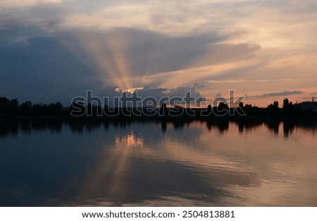 The sun's rays break through the clouds near the lake