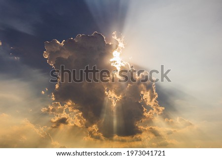 The sun's rays passing through the clouds and shining form an interesting light pattern against the sky. 