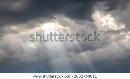 The sun's rays penetrate through the dark clouds during sunset, panorama