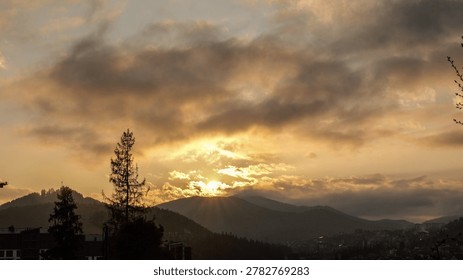 The sun's rays pierce through dramatic clouds, illuminating a serene mountain landscape at dusk