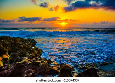 The Sun's Reflection On The Foamy Surf On A Rocky Florida Beach.