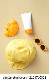 Sunscreen baby cream tube, sunglasses, panama hat, sand mold on beige background. Flat lay, top view. Sun protection concept.