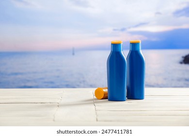 Sunscreen bottles on wooden table and beautiful blurred sea background. - Powered by Shutterstock