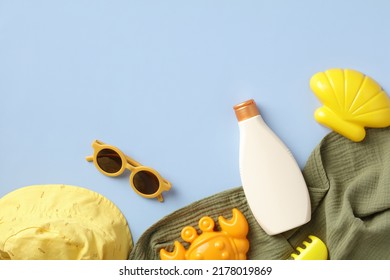 Sunscreen Cream Bottle With Glasses, Sand Molds, Panama Hat, Towel On Blue Table. Flat Lay, Top View. Sun Safety, Kids Sun Protection