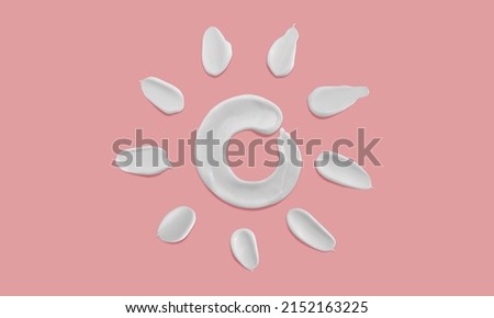 Sunscreen cream sun shape smears on pink background, white moisturiser strokes