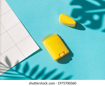 Sunscreen Stick On The Blue Wet Background With Tropical Leaves Shadows. Summer Vacation Cosmetics Concept. Top View	