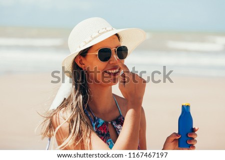 Sunscreen, sunblock. Woman putting solar cream on nose smiling beautiful summer day. Skincare. Girl applying sun cream