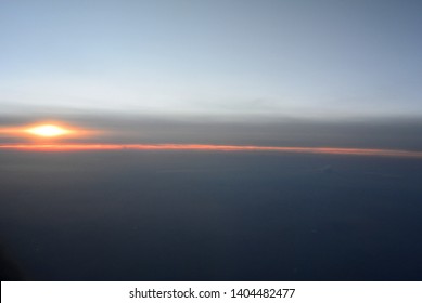 Sunset above the clouds. View in the evening from the window of the plane flying at high altitude