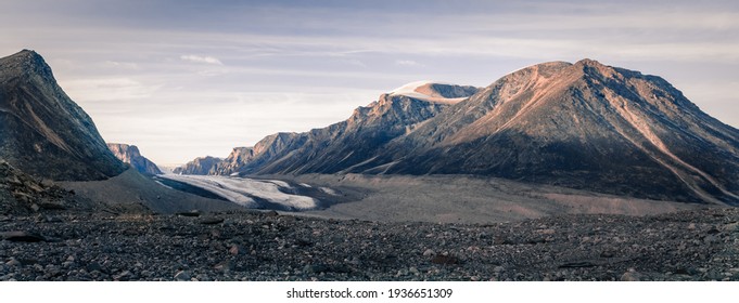 Sunset above above remote arctic valley of Akshayuk Pass, Baffin Island, Canada. Last rays of light on the peaks around Highway glacier. Arctic summer in the wild of the far north. - Shutterstock ID 1936651309