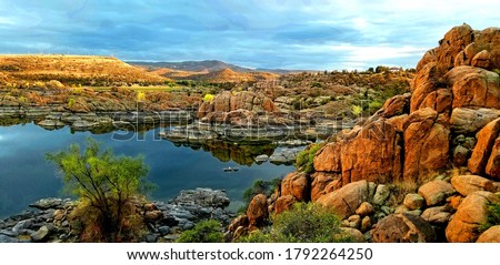 Sunset after late summer storm at Lake Watson, Prescott, Arizona with golden rocks over still blue skies with sky reflection