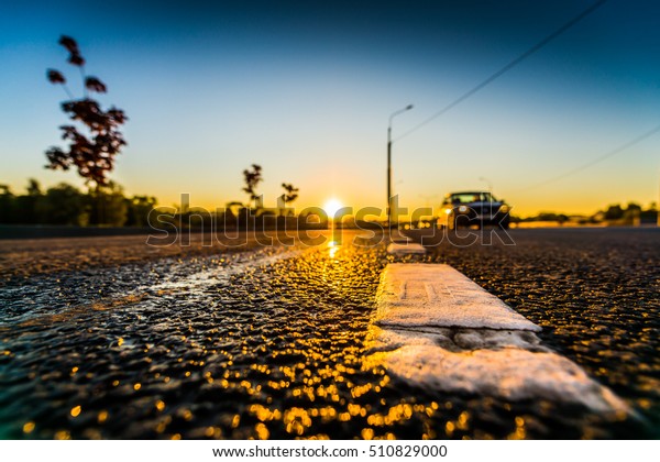 Sunset after\
rain, the car is moving on the highway. Wide angle view of a\
close-up from the level of the dividing\
line