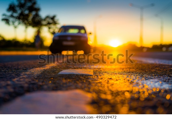 Sunset after rain, the car
parked on the roadside. Close up view from the level of the
dividing line