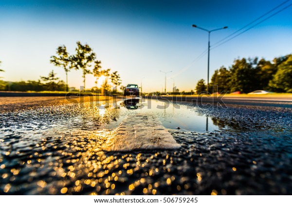 Sunset after rain, the car\
parked on the roadside. Wide angle view of the level of the\
dividing line