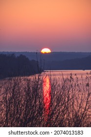 Sunset Autumn Landscape On A Wide River With Reflections And A Bright Sun Setting Beyond The Horizon. Rural Scene Photo From High Altitude.