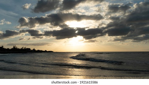Sunset in the beach with clouds and waves