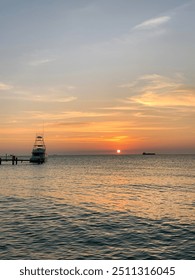 Sunset at the beach sun setting over the ocean with calm sea yatch dawn coastal wave cool holiday sky light orange golden evening day time look calm nature tropical beautiful
