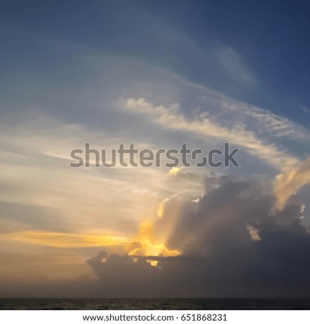 A Sunset Behind Clouds That Overlooks an Ocean
