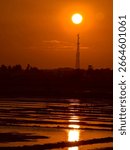 Sunset behind the communication tower with reflection on the water 