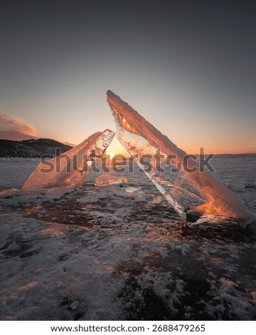 Sunset behind ice formations on a frozen lake, creating a stunning natural spectacle with warm hues reflecting on the ice surface.