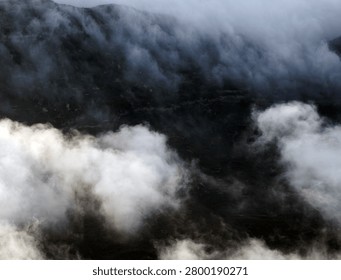 Sunset behind layered clouds over mountains. Golden light breaks through sky, creating a peaceful and dramatic silhouette scene.